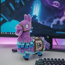 Load image into Gallery viewer, Fortnite Loot Llama 6 inch soft plush toy with vibrant colors and detailed stitching on a desk next to a keyboard and computer screen.