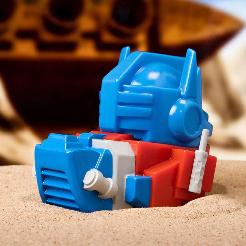 TUBBZ Transformers Optimus Prime Collectible Duck toy on sand.