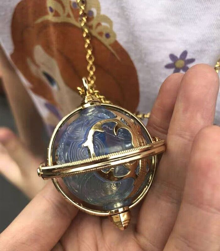 Golden Chronosphere Necklace from Alice Through The Looking Glass with intricate swirling glass design.
