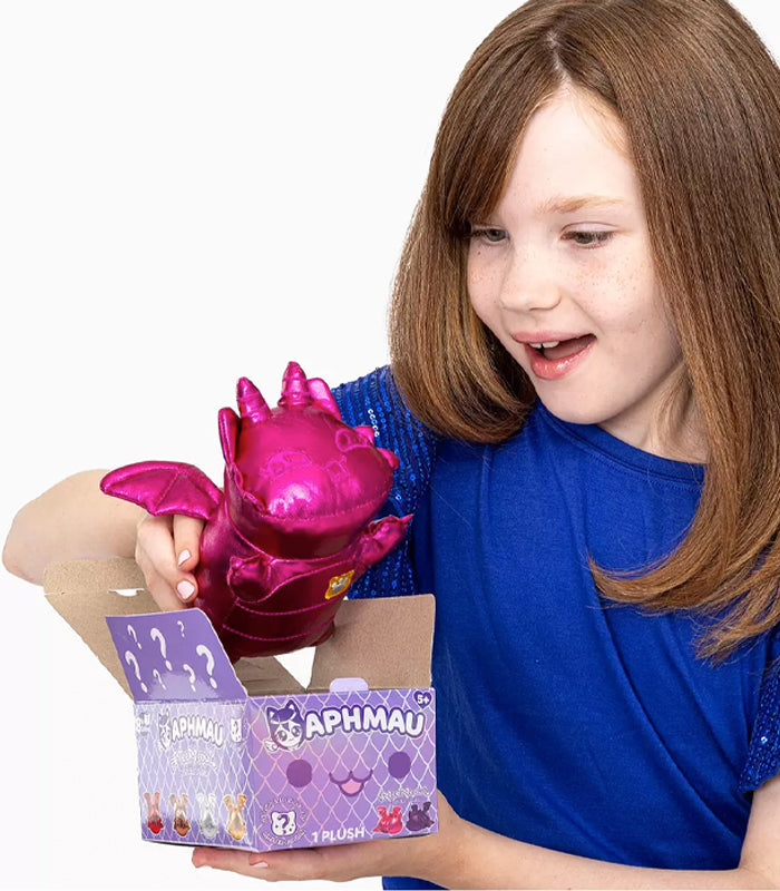 Girl holding pink Aphmau Gemstone Dragons MeeMeows 6-inch plush toy emerging from purple box