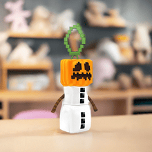 Load image into Gallery viewer, Minecraft 5 Inch Snow Golem Bag Hanger Plush with pumpkin head and clip, displayed on a table.
