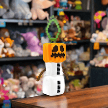 Load image into Gallery viewer, Minecraft 5 Inch Snow Golem Bag Hanger Plush with pixelated design and sturdy clip, displayed in a toy store.

