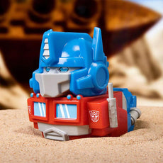 TUBBZ Transformers Optimus Prime Collectible Duck with blue and red color scheme on sand background.